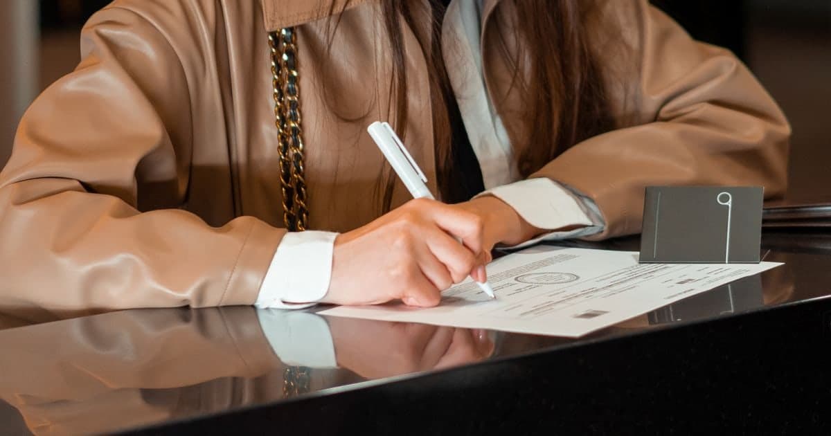 Una mujer firma un documento con sello sobre el mostrador de una oficina